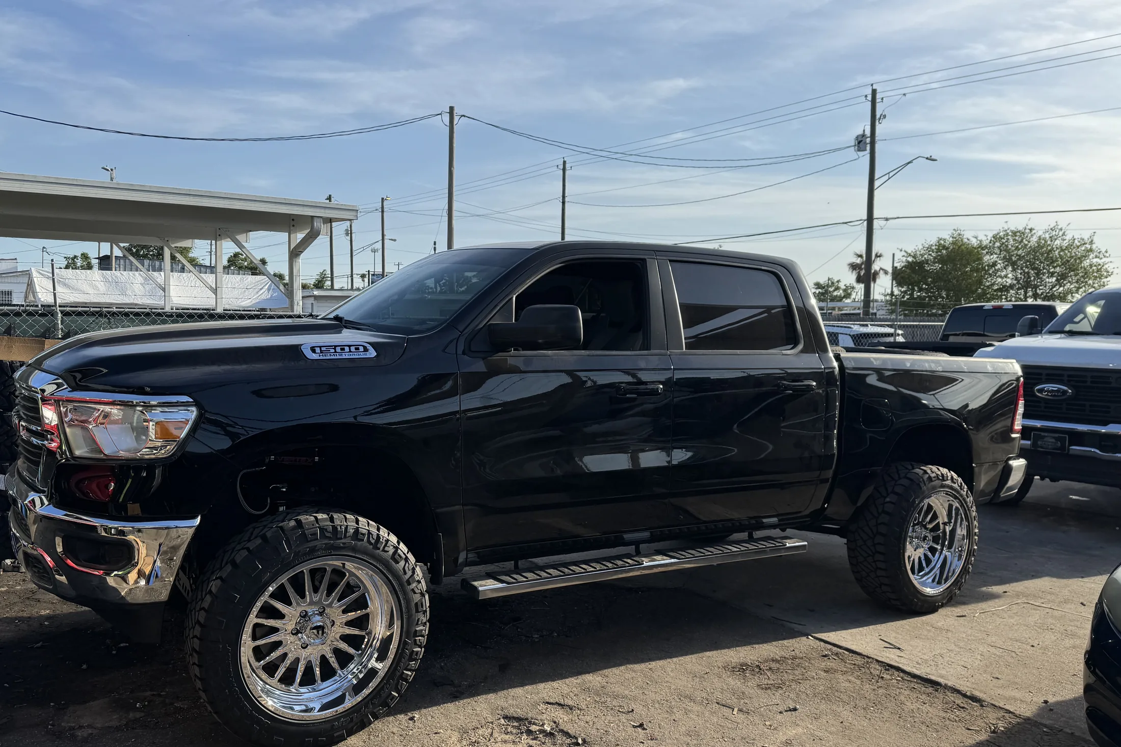 A black Ram crew cab on a lift kit and polished wheels outside the shop